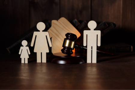 Figurines of parents standing next to a child, next to a gavel