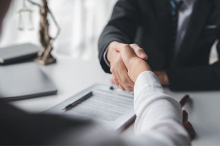 A lawyer shaking hands with a client over a signed document