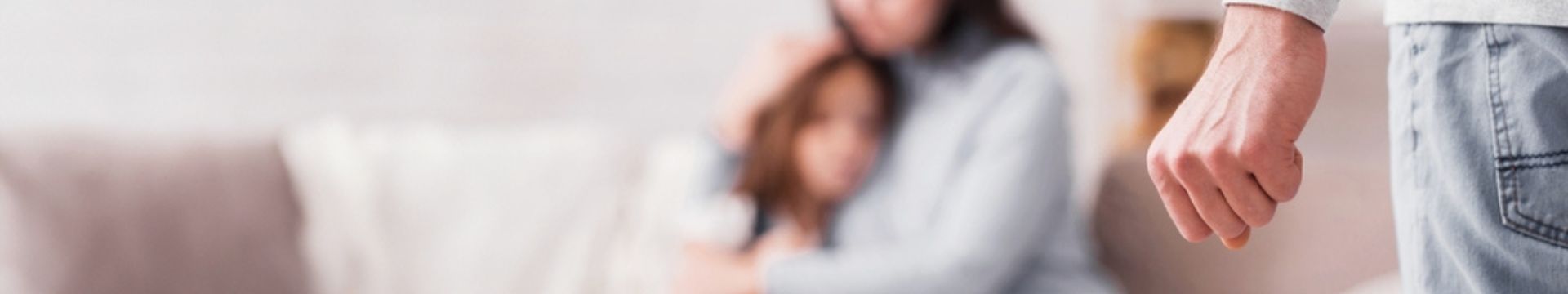 man with fist facing his wife holding his daughter on the sofa
