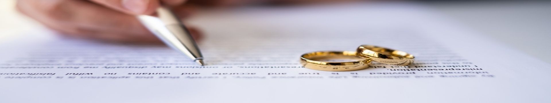 signing divorce paperwork with wedding rings.