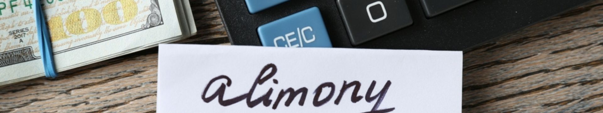 Money, a calculator, and a sign reading 'Alimony' on a desk